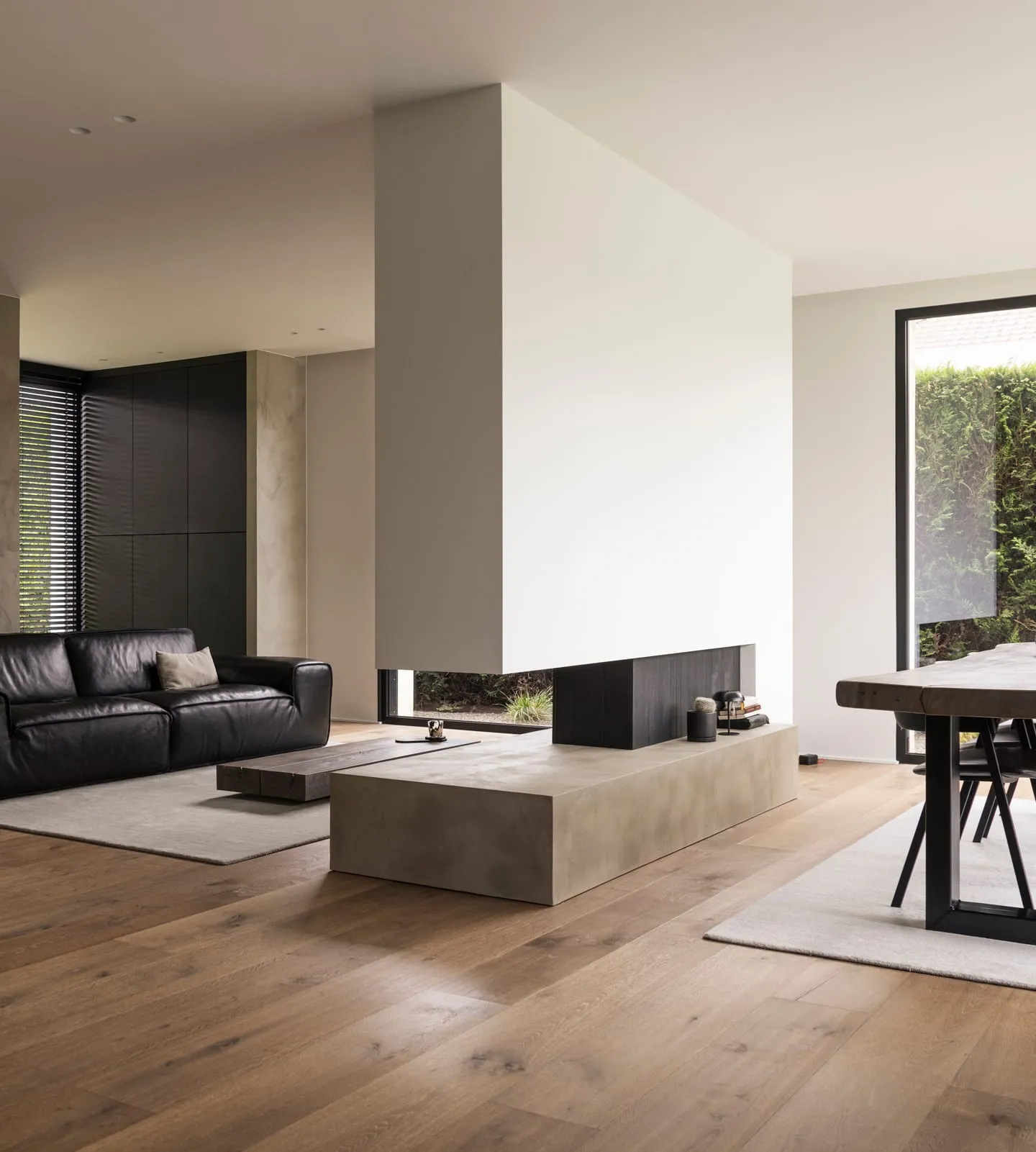 Séjour et salle à manger de la villa contemporaine, murs en béton ciré, parquet en chêne et grandes baies vitrées sur le jardin
